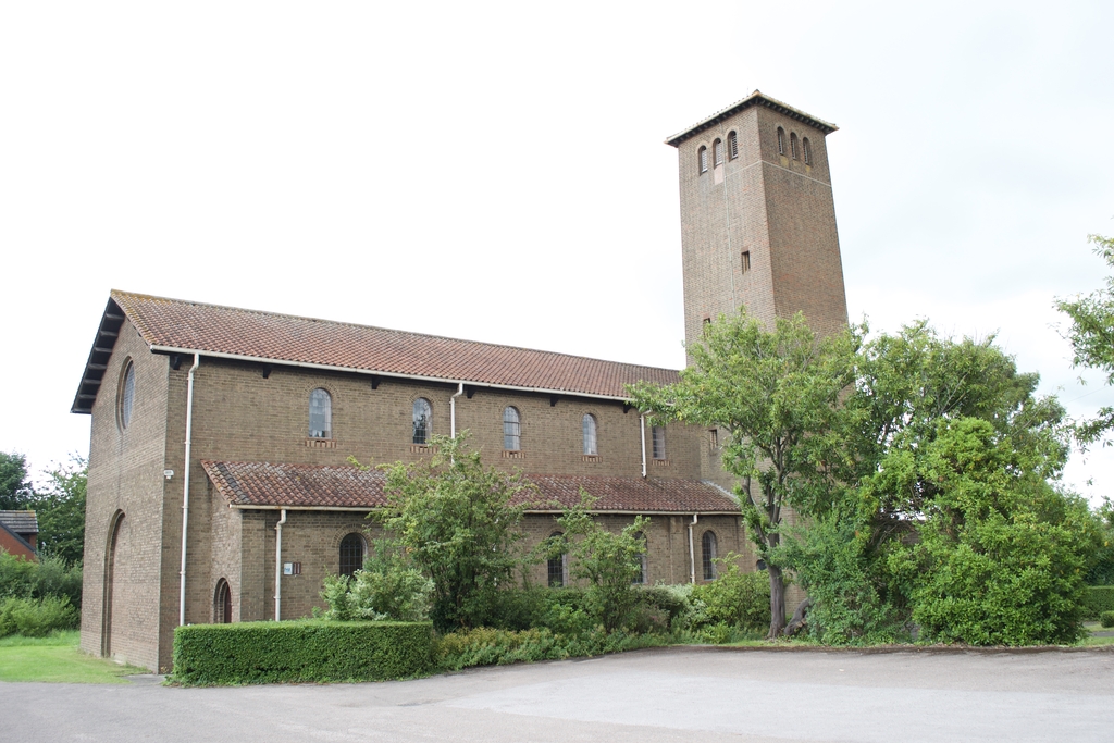 St Oswald's Church, a brick building with a tall square tower, seen from the car park